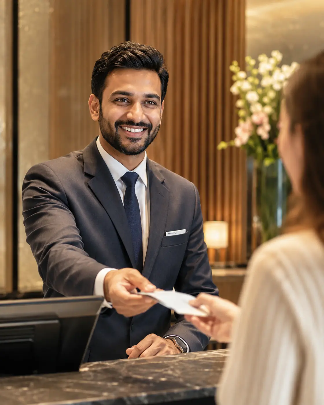 Hotel front-desk colleague handing a key card to a guest.